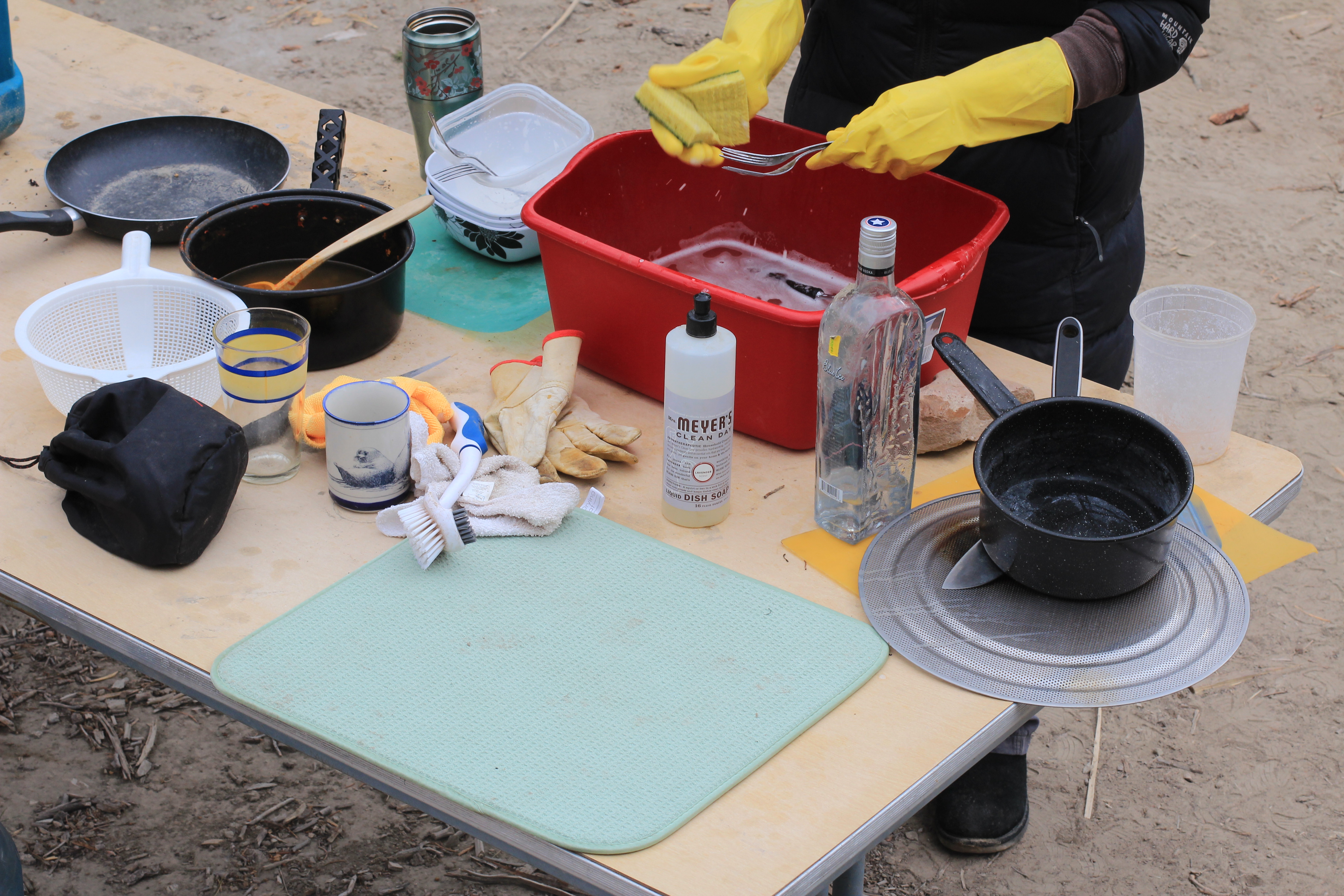 Washing dishes outdoors can be a pain in the arse, but you just need to find your groove. Our method: gloves (to protect our soft climbing hands) and a red bin.
